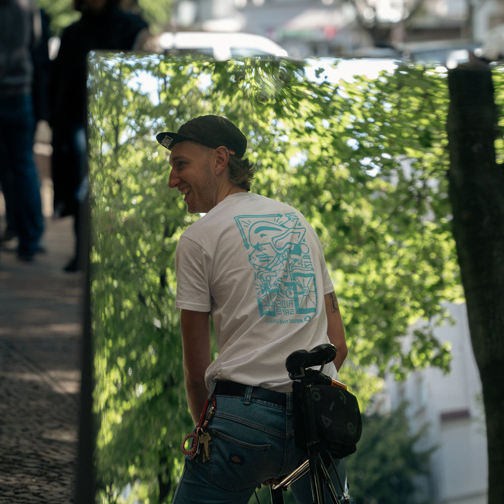 Man wearing velo T-shirt, pictured through mirror, with green city background