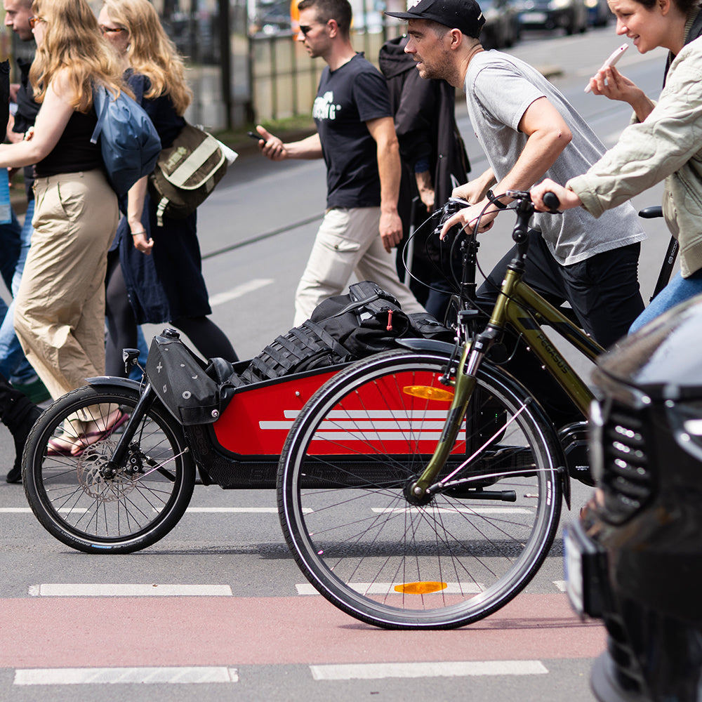 man on cargo bicycle in city traffc crossing the road