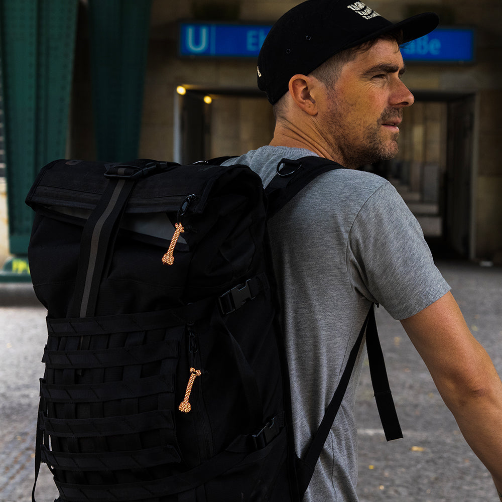 man wearing backpack in front of a metro entrance
