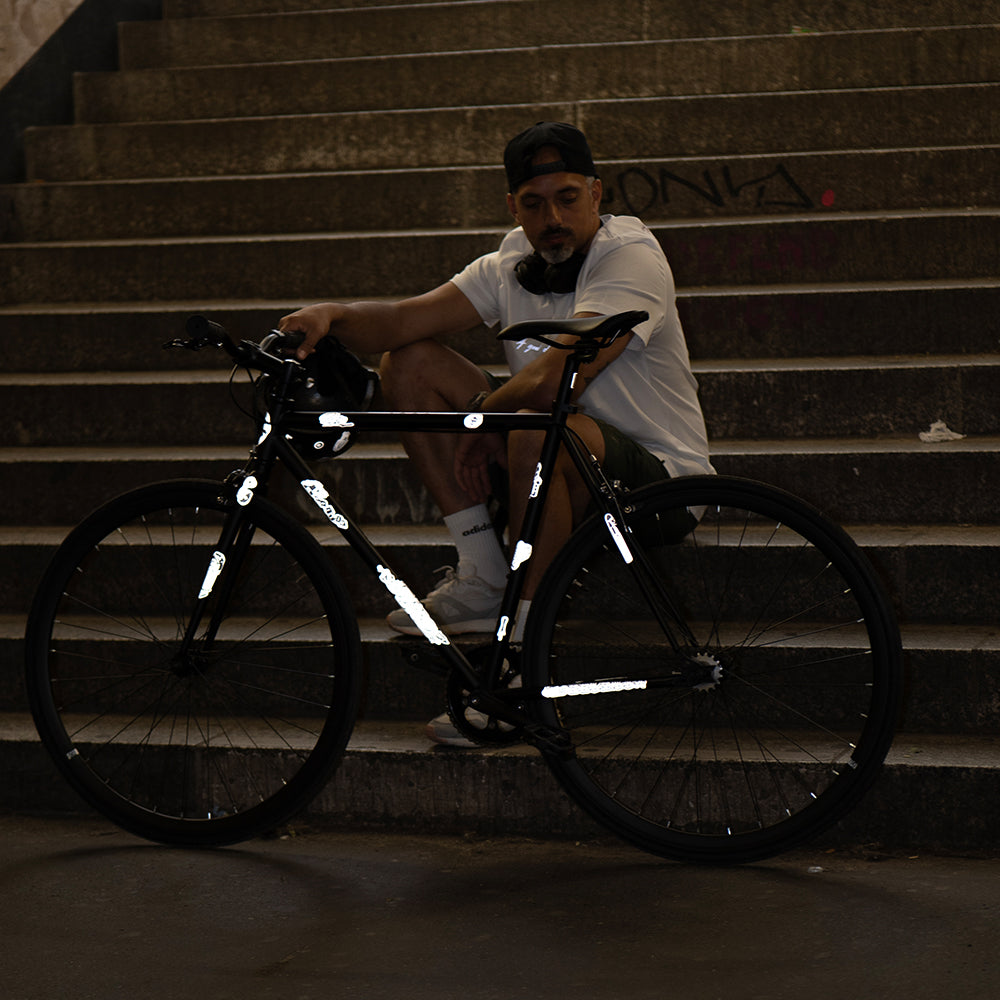 reflective sticker set on bicycle with Artist MrP holding it and sitting on staircase