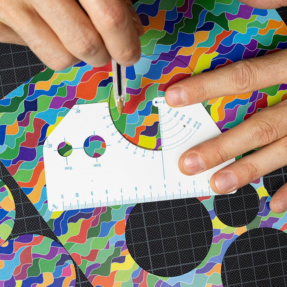 Hand malt mit Hilfe einer Schablone Kreise auf bunte Folie