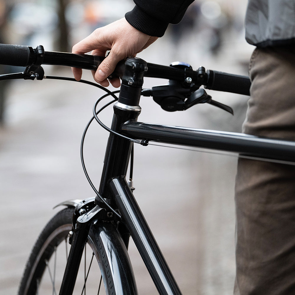 Man holding bicycle with black reflective stripes.