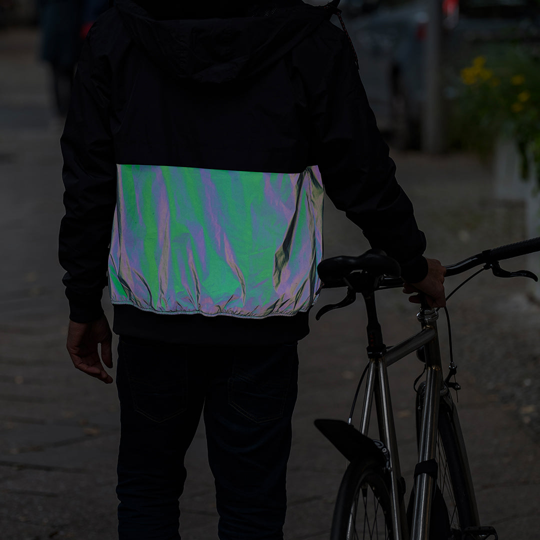 Mann nachts von hinten mit teilweise irisierender reflektierender Jacke