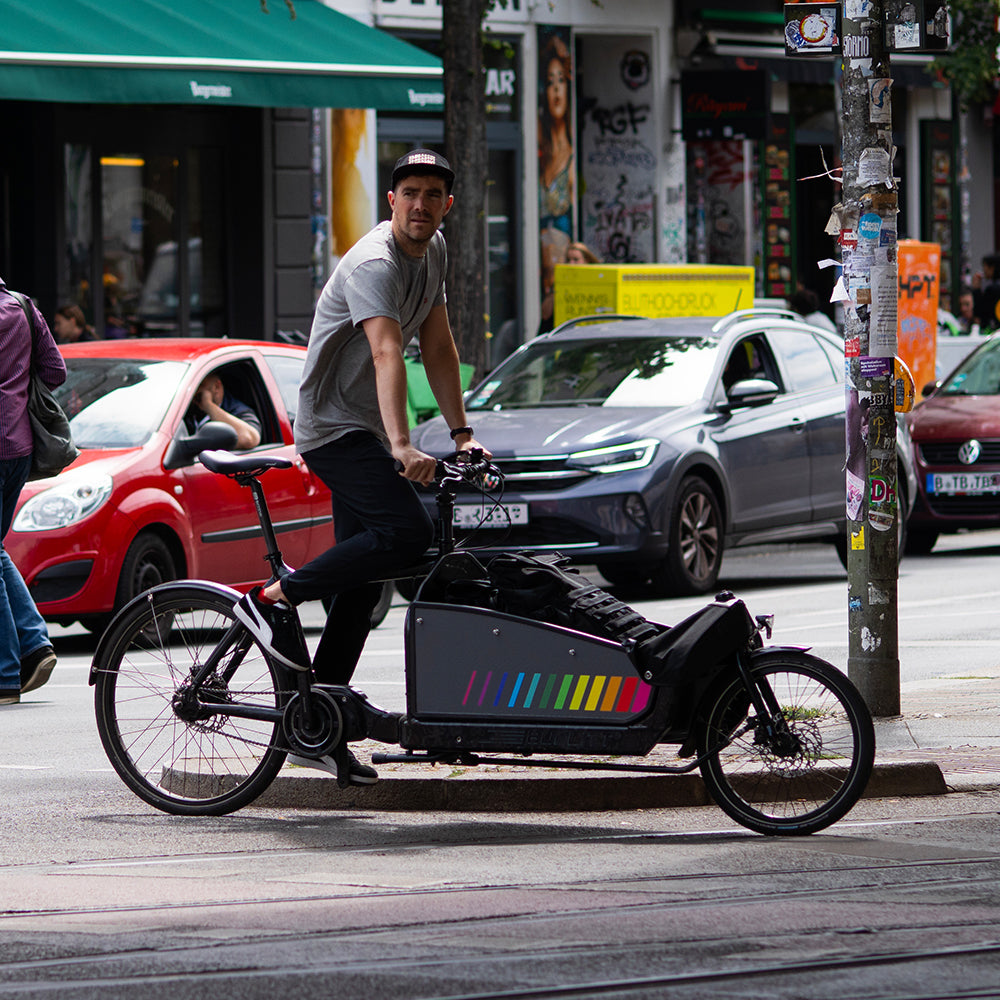 Man on cargo bicycle in city traffic