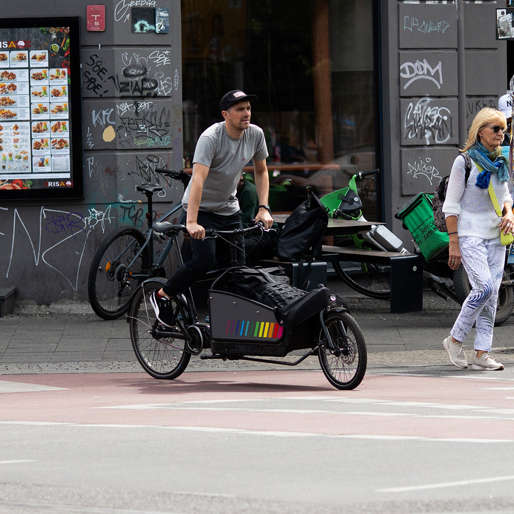 man crossing the road on cargo bicycle in city traffic