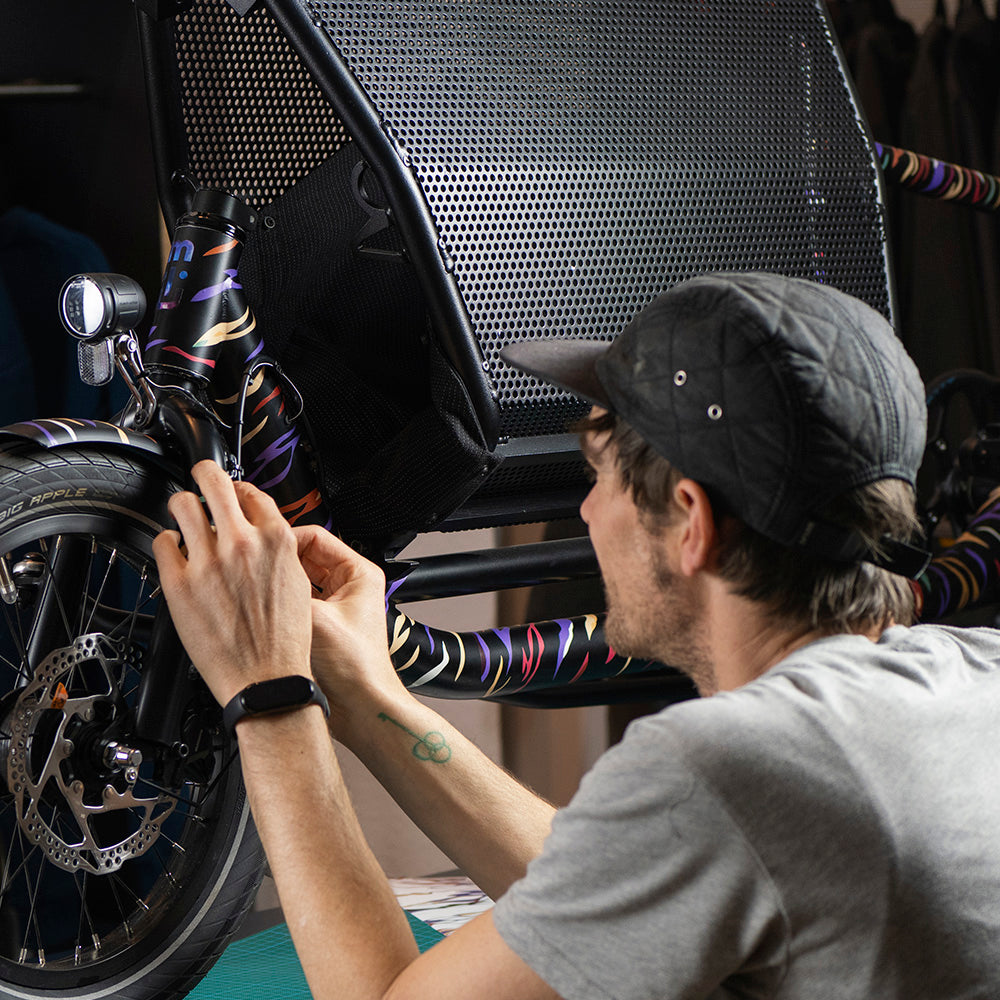 man sticking reflective design on cargo bicycle