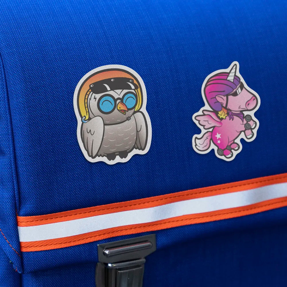 Reflektierende Aufkleber Textil Stoff Eule „Olli“ und Einhorn „Juno“, aus der Produktserie „Reflective Friends“ die auf einen blauen Schulrucksack geklebt sind. Von REFLECTIVE Berlin.