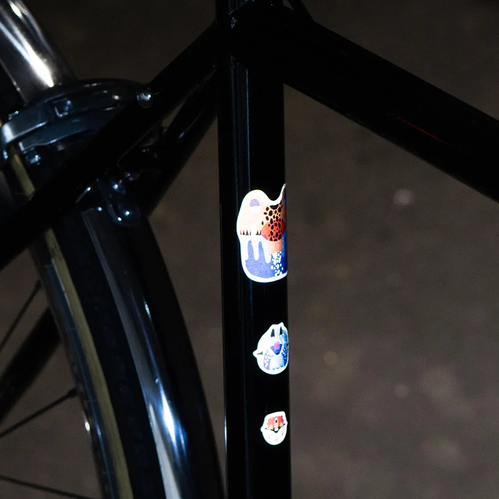 Reflektierende Aufkleber Künstleredition „Kurihara“ auf schwarzem Fahrrad Rahmen vor unscharfem Hintergrund. von REFLECTIVE Berlin