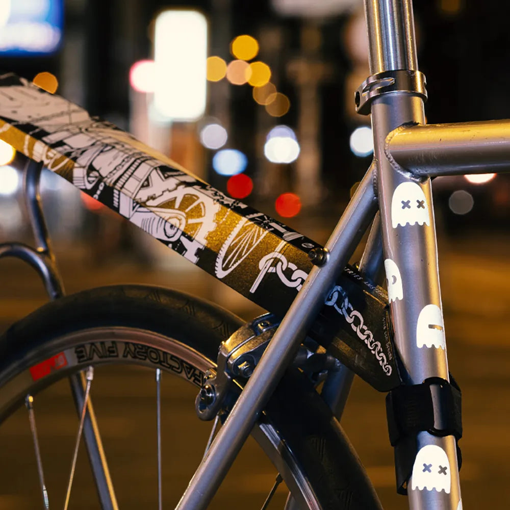 Reflektierender Aufkleber „Geister“ in Farbvariante „weiß“ auf silbernen Fahrradrahmen mit verschwommenen Hintergrund und Straßenlichtern von REFLECTIVE Berlin.