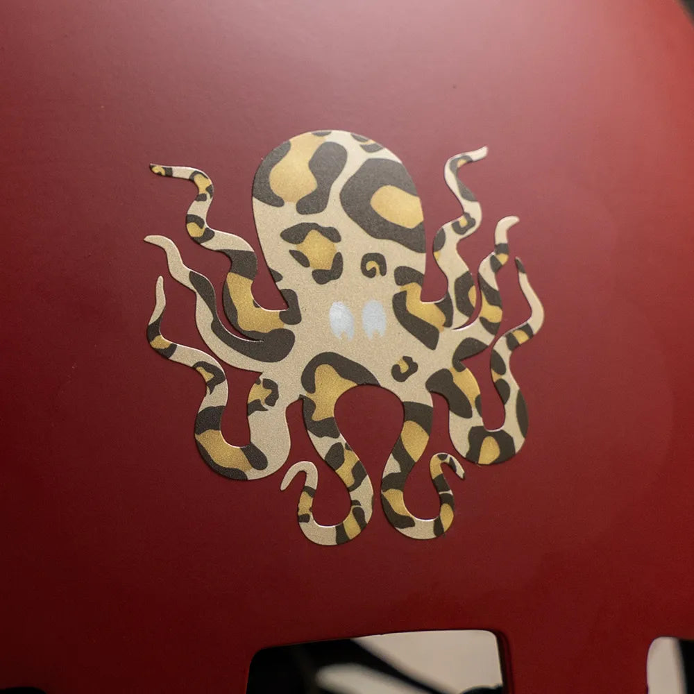 Reflektierender Aufkleber „Kraken“ in Farbvariante „Leo" auf einem roten Fahrradhelm im Detail von REFLECTIVE Berlin.