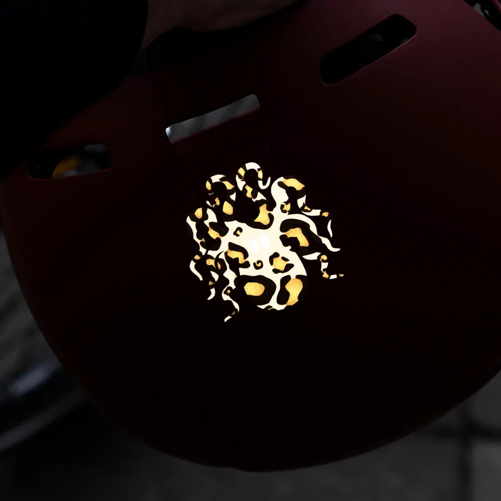 Reflektierender Aufkleber „Kraken“ in Farbvariante „Leo" auf einem roten Fahrradhelm von REFLECTIVE Berlin.