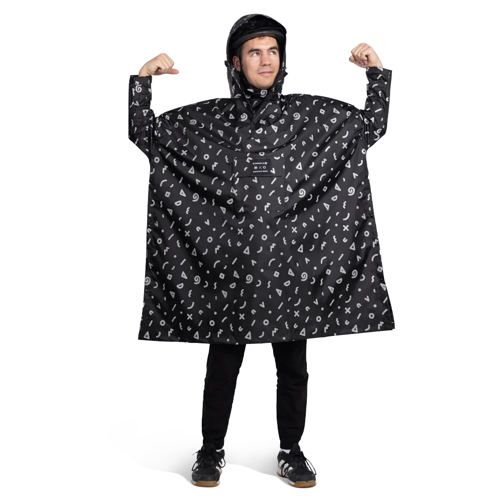reflektierender Fahrrad Regenponcho in Farbvariante „Doodle“ getragen von einer Person, die einen Fahrradhelm trägt und die Ihre Arme hebt. Kollaboration von Bomance und REFLECTIVE Berlin.