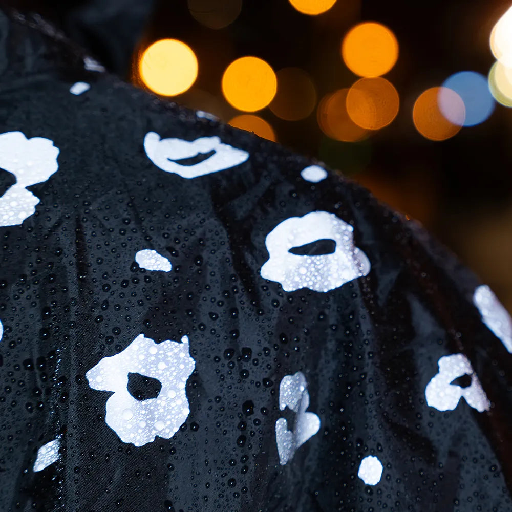 Schulter Detail von reflektierendem Fahrrad Regenponcho in Farbvariante „Leo“. Auf dem Regenponcho sind Regentropfen. Das Bild wurde bei Dunkelheit mit Blitzlicht aufgenommen, um die Reflexion des Ponchos hervorzuheben. Kollaboration von Bomance und REFLECTIVE Berlin.
