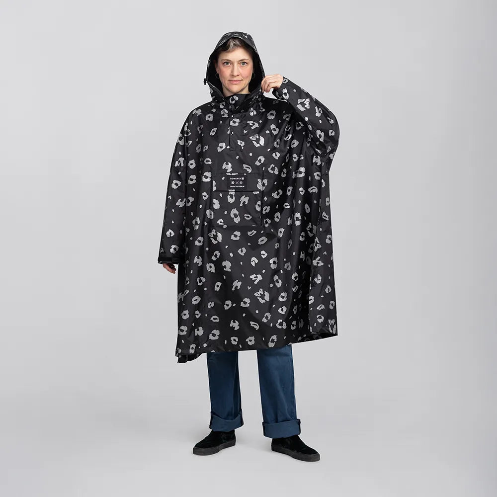 reflektierender Fahrrad Regenponcho in Farbvariante „Leo“, getragen von einer Person, die frontal in die Kamera schaut und die Kapuze justiert. Kollaboration von Bomance und REFLECTIVE Berlin.