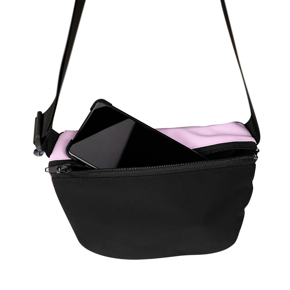 reflektierende Gürteltasche/fanny pack/Pouch in Farbvariante „soft rosa“ in Rückansicht. Ein Smartphone schaut teilweise aus der Rücktasche mit Reißverschluss heraus. Arrangement von REFLECTIVE Berlin.