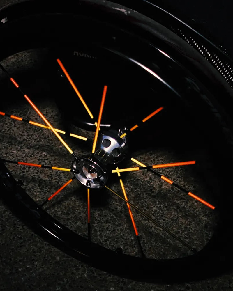 Reflektierender Speichen Aufkleber „Spokes“ in Farbvariante „Feuer“ auf den Speichen von einem Rollstuhl. Blitzlicht hebt die Reflexion der Speichen Aufkleber hervor. Von REFLECTIVE Berlin.