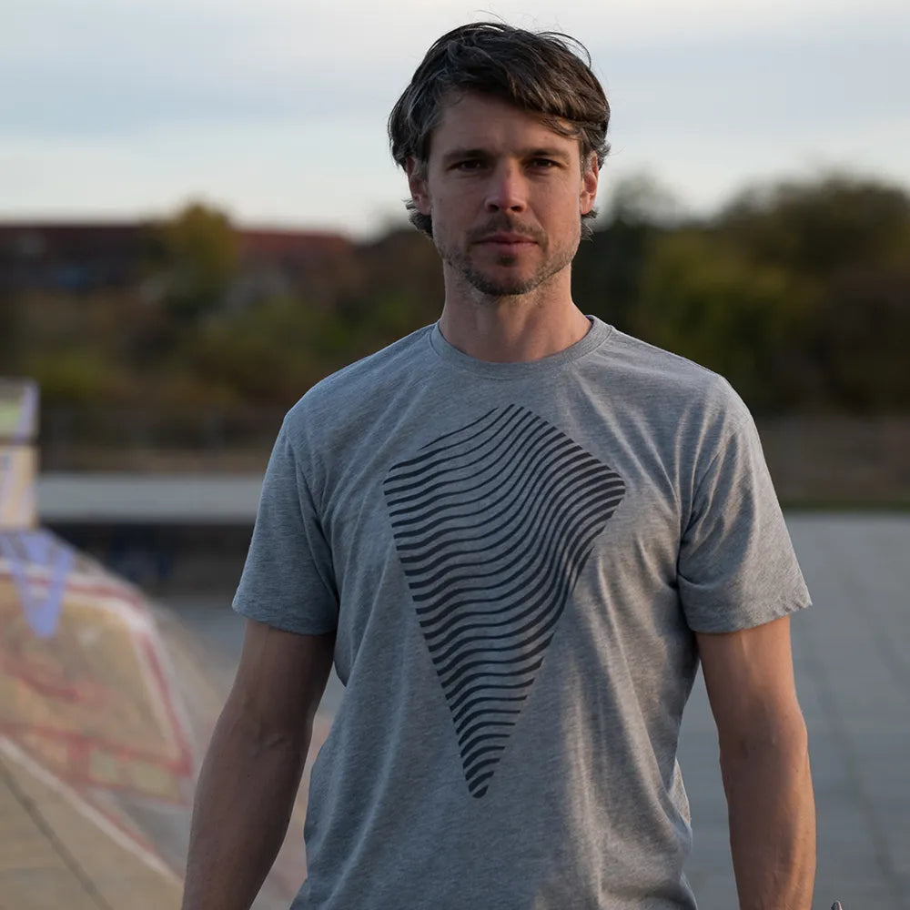 Person trägt das reflektierende T-Shirt Dune in Grau von REFLECTIVE Berlin bei Tageslicht. Die T-shirt Reflexion ist nicht sichtbar.