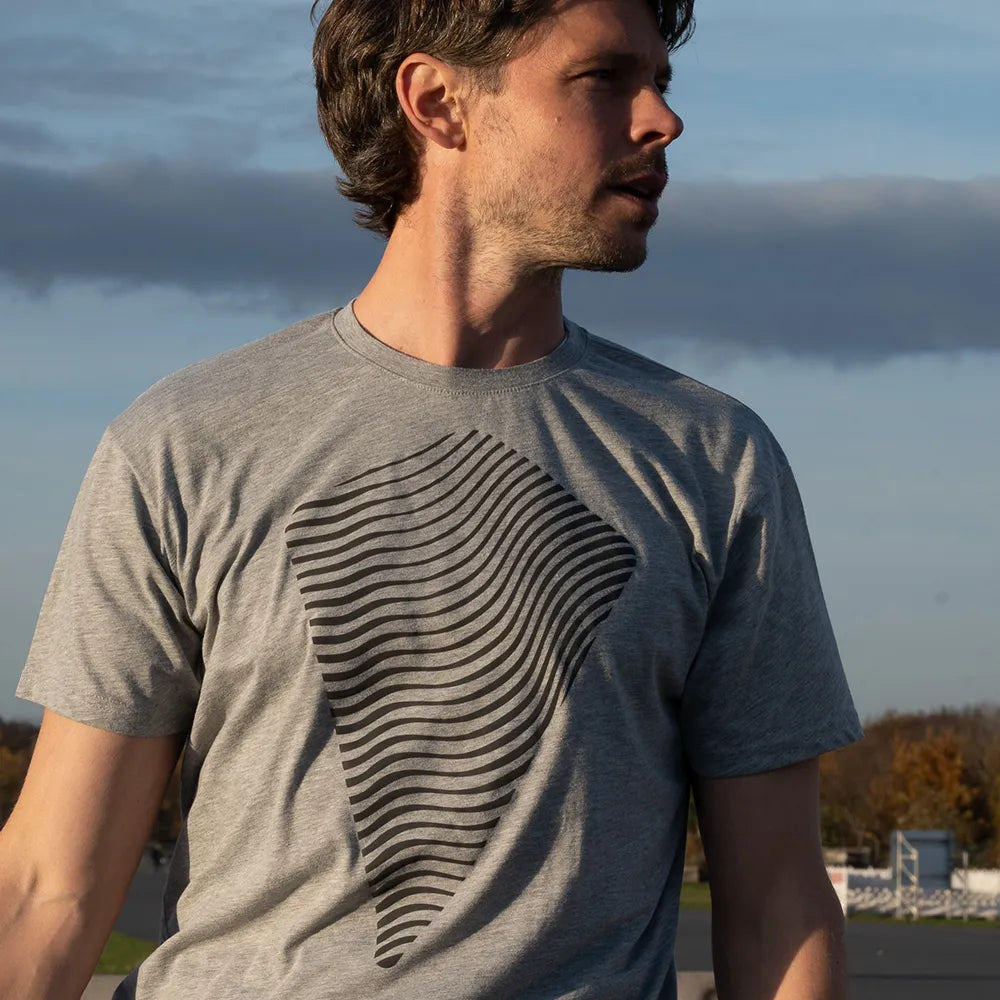 Person schaut nach rechts und trägt das reflektierende T-Shirt Dune in Grau von REFLECTIVE Berlin bei Tageslicht.