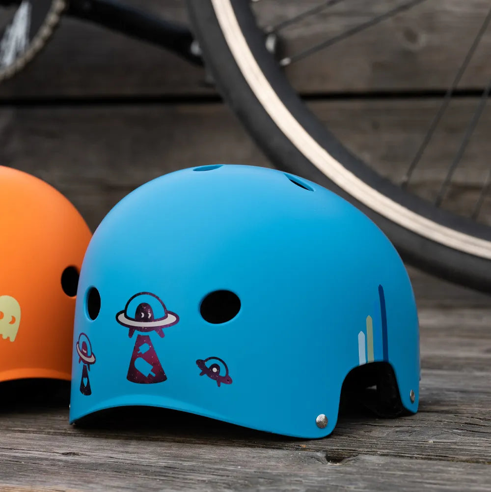 Reflektierender Aufkleber „UFO“ in Farbvariante „Weltraum“ auf Rückseite von einem blauen Helm vor unscharfem Hintergrund von REFLECTIVE Berlin.