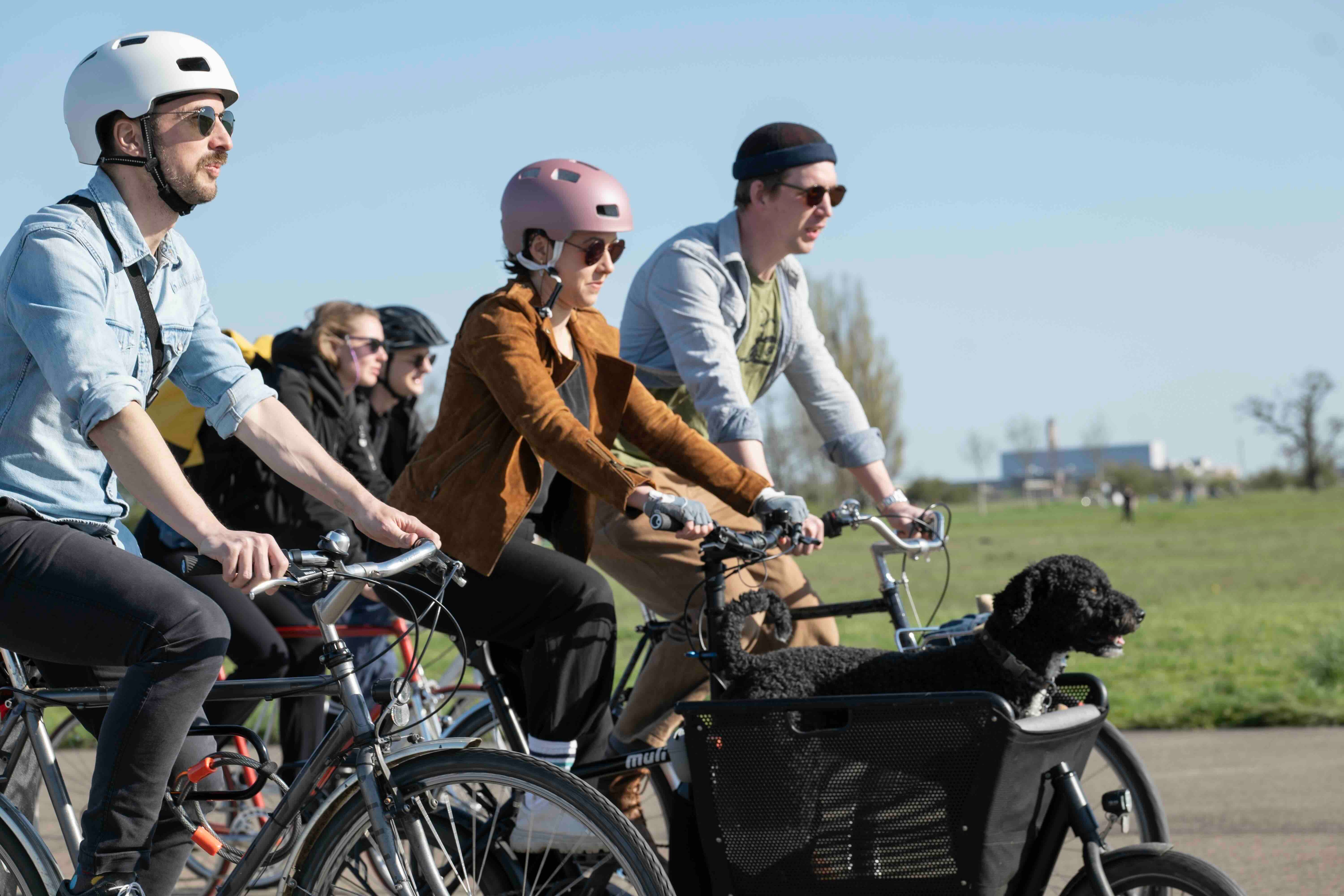 Mehrere Fahrradfahrer*innen mit Hund radeln über das Tempelhofer Feld