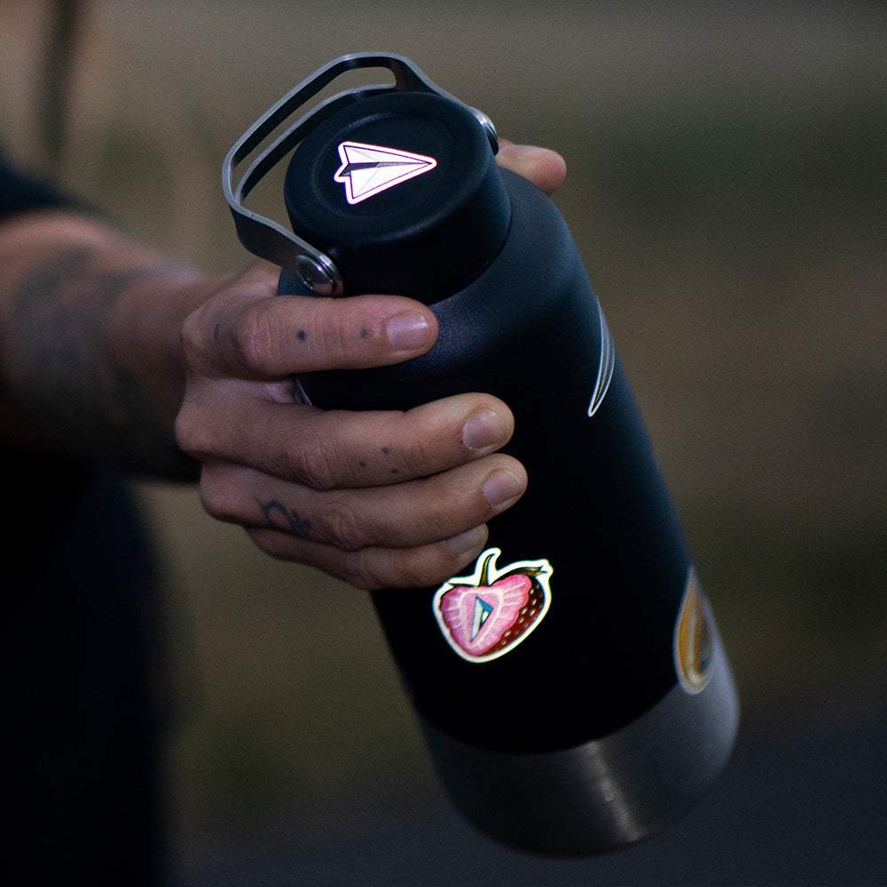 hand holding a metal water bottle with a reflective paperplane design