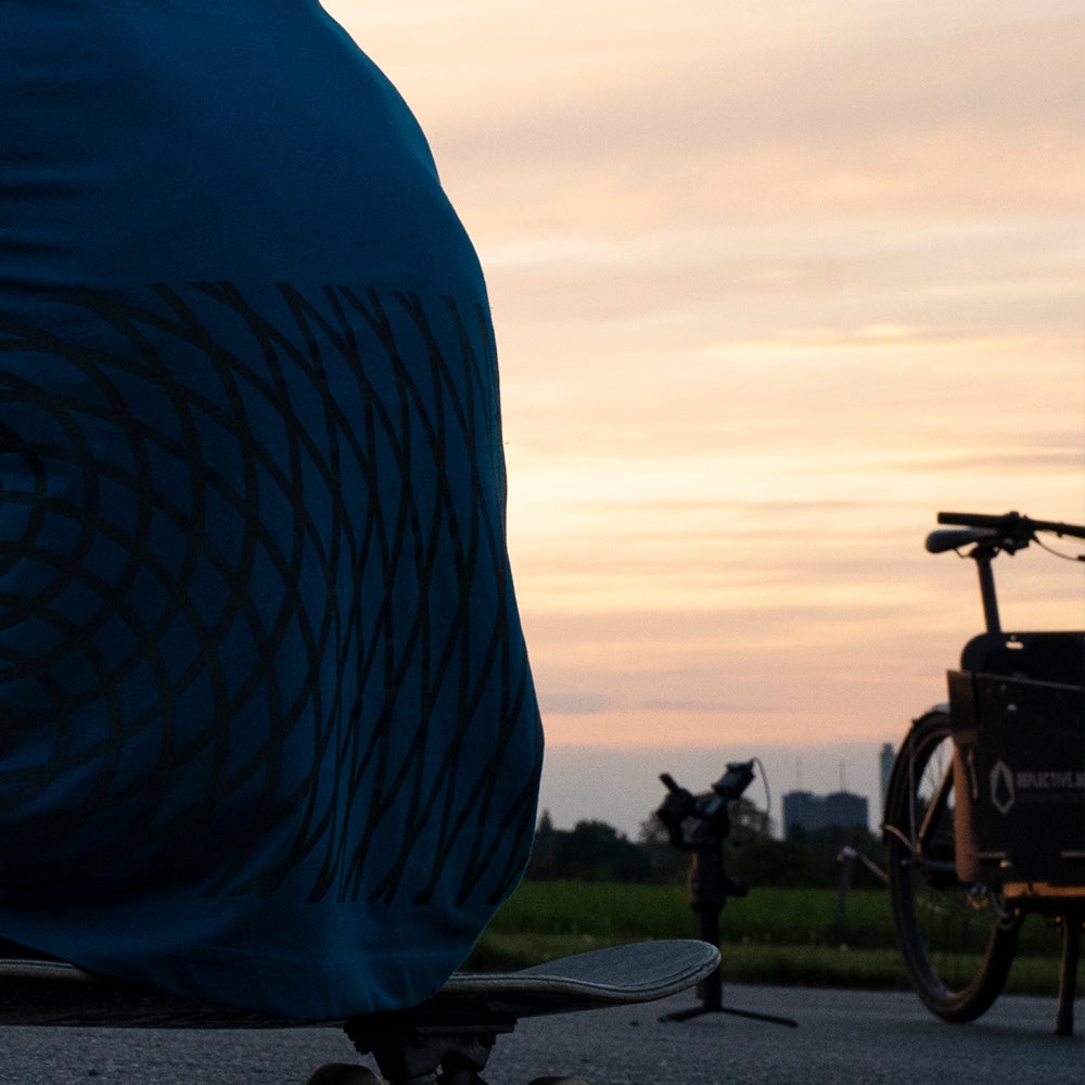Anschnitt von jemandem der auf Skateboard sitzt, rechts sieht man ein Lastenrad