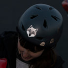 Frau mit grauem Helm und reflektierendem Wolf Aufkleber vorne, sieht nach unten,