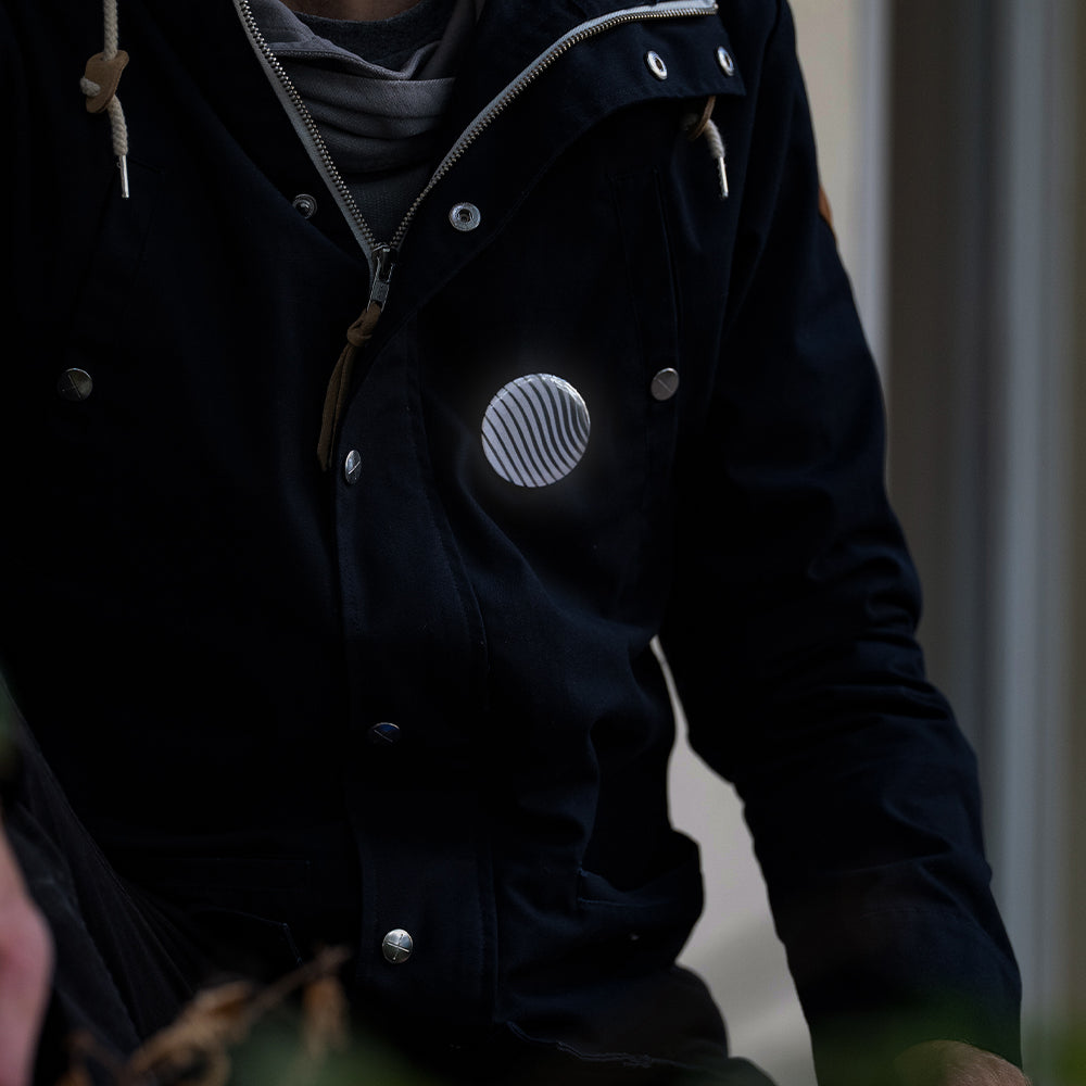 man with jacket wearing reflective button, walking in street