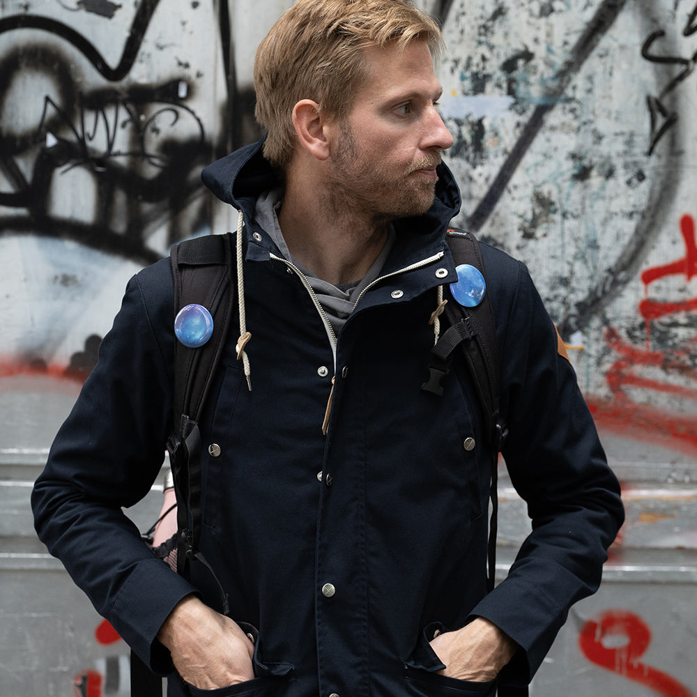 Man wearing dark blue jacket in front of graffity wall in Berlin