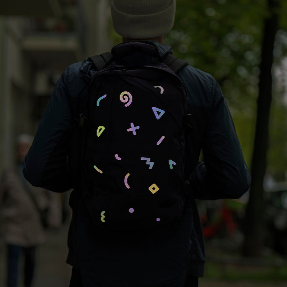 Reflective textile sticker on dark backpack, man silhouette in city with blur