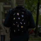 Reflective textile sticker on dark backpack, man silhouette in city with blur