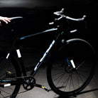 Black bike with reflective stickers held by man, dark background