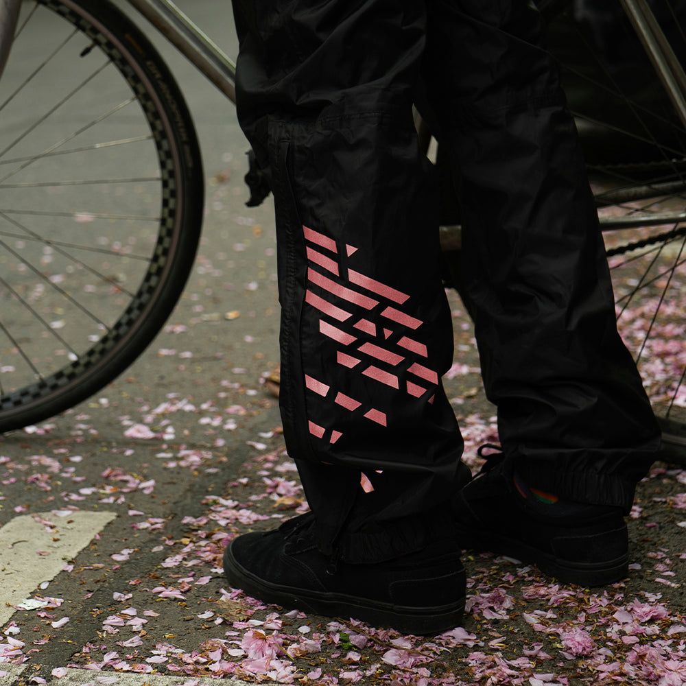 closeup of reflective stickers on rain pants with street and pink leaves