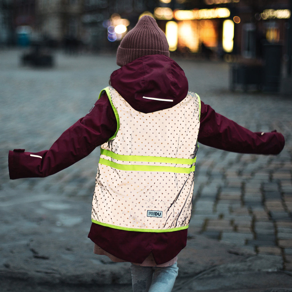 Kid wearing a reflective jacket, dancing in city