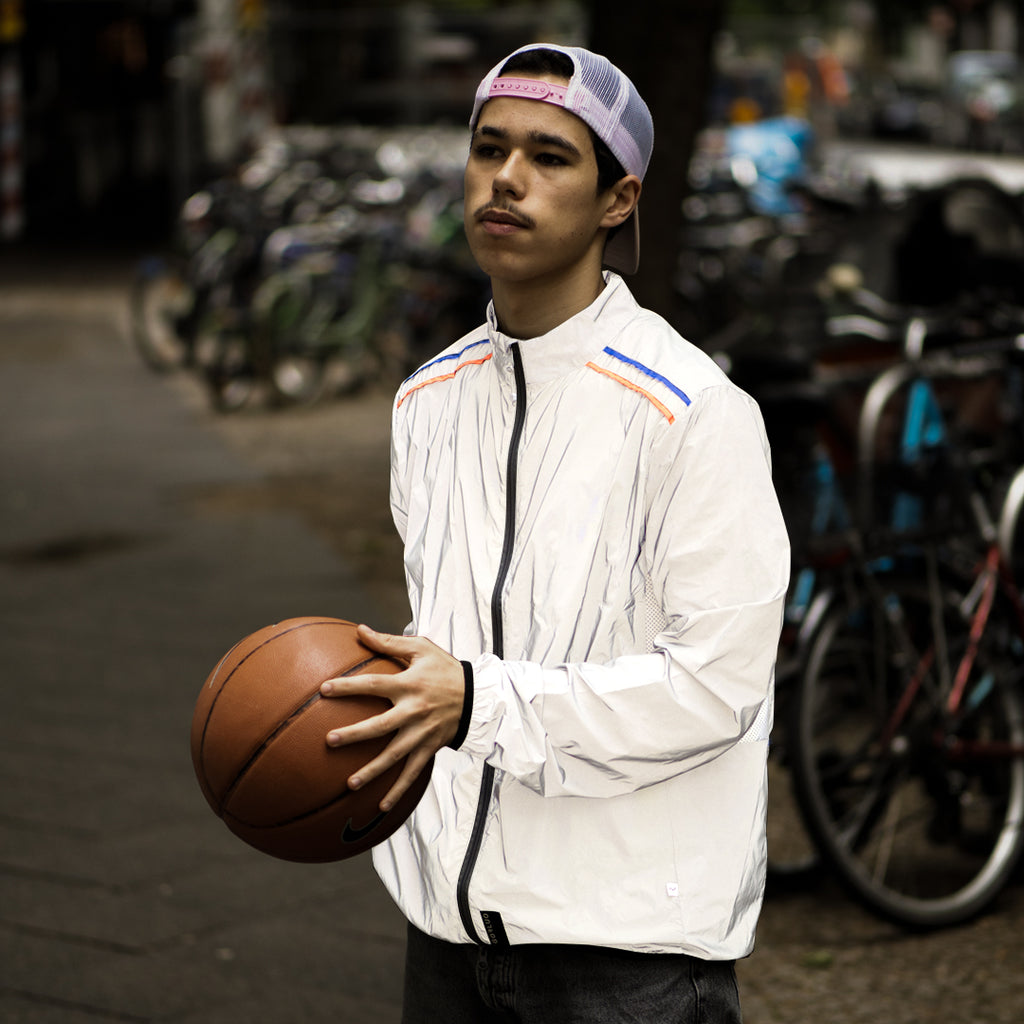 Young man wearing a reflective jacket with basketball.
