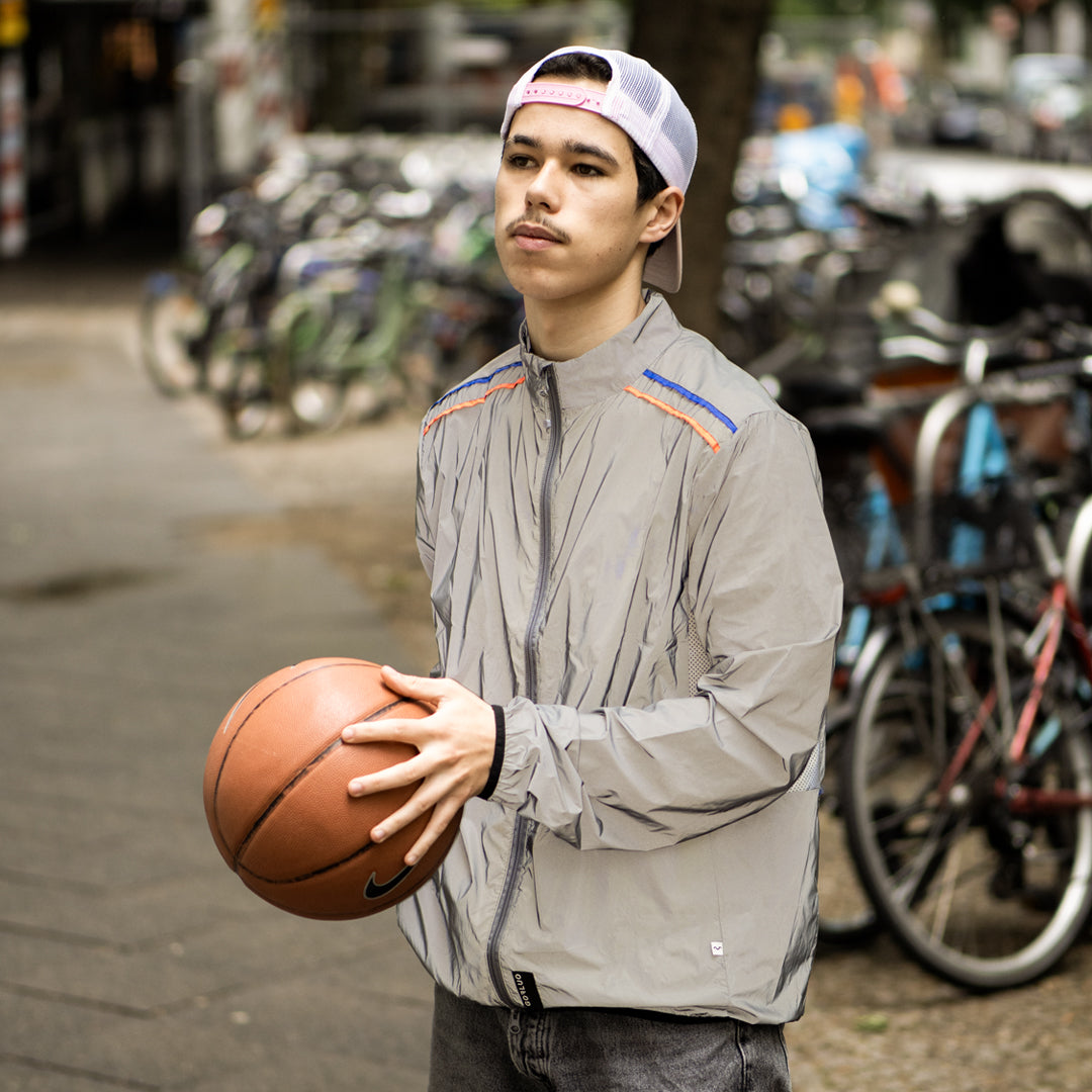 young man wearing a sport jack with basketball, blurry background and bicycles