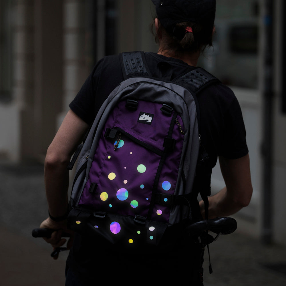 Man wearing bag with rainbow reflective stickers shining