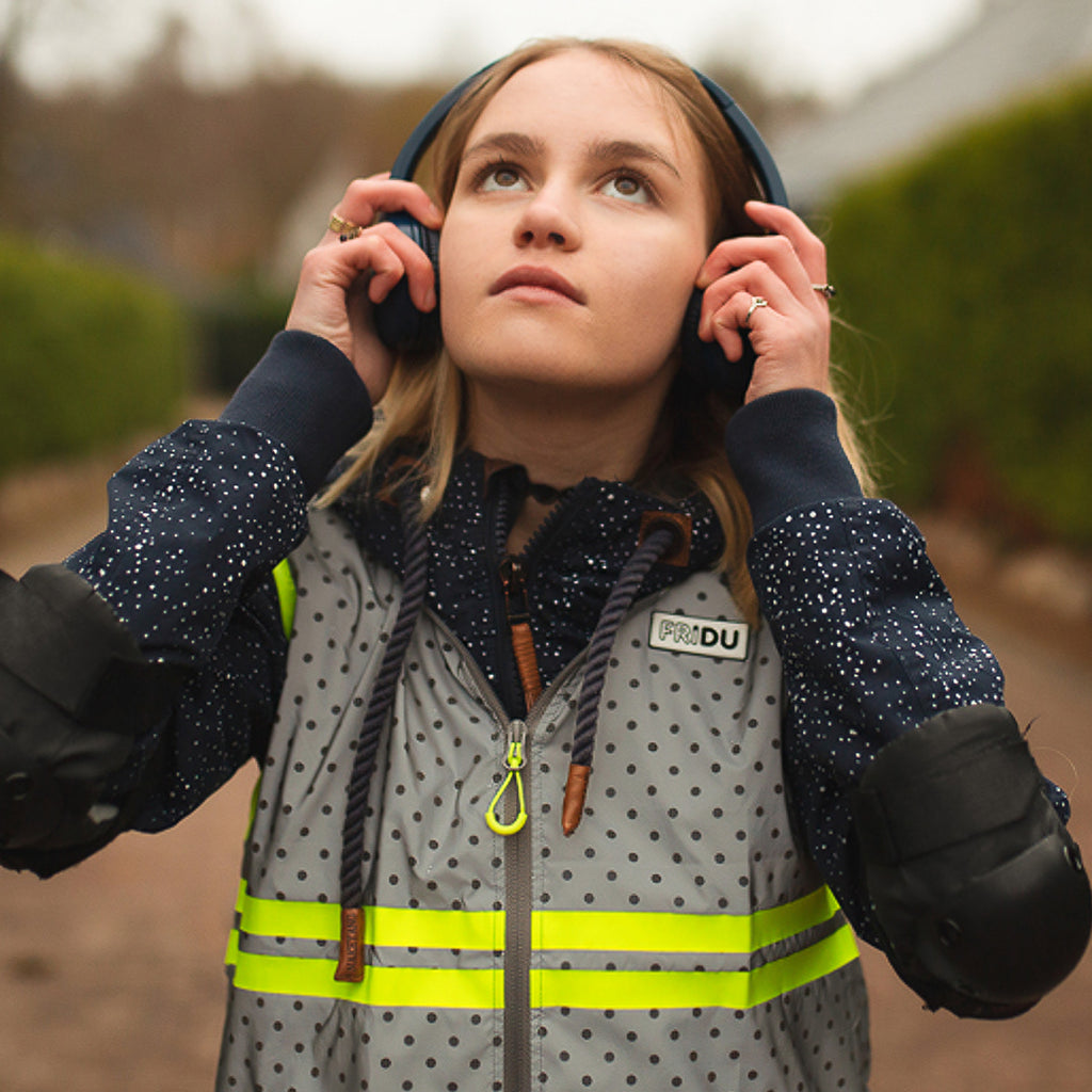 Young girl listening to music with headphones and wearing protection for roller blading