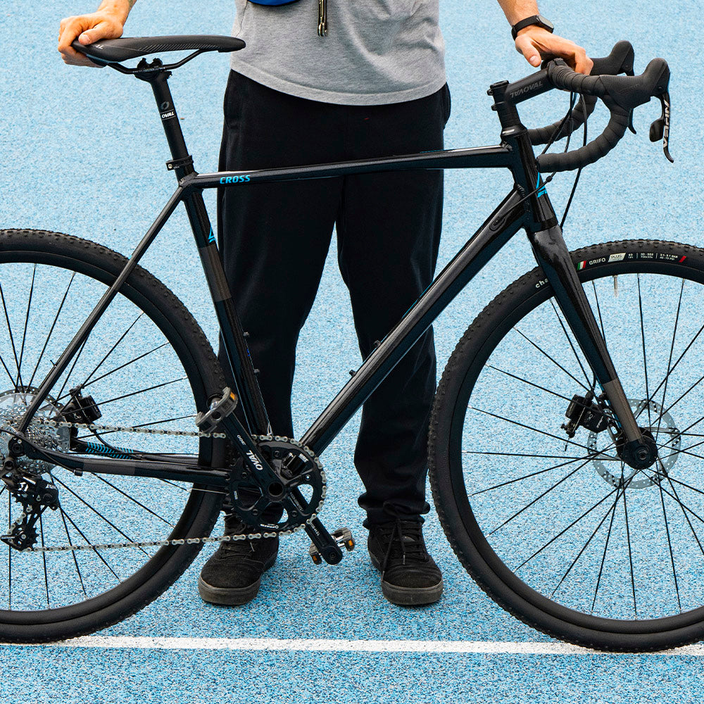 Man holding black bicycle, with blue background 