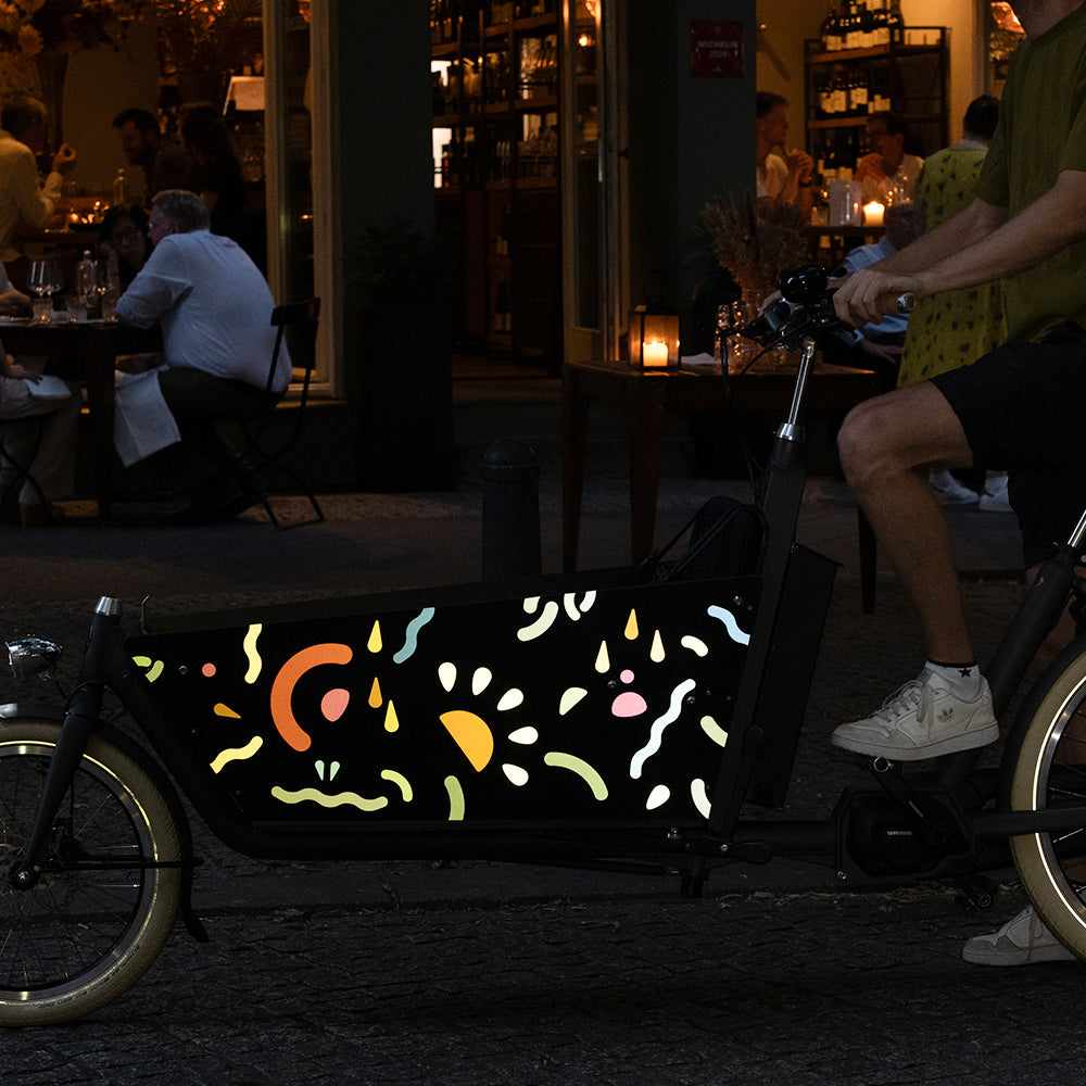 Reflective ticker totem applied on side box of cargo bicycle in night street