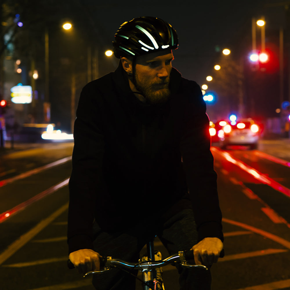 Fahrradfahrer bei Nacht im Straßenverkehr mit reflektierendem Helm