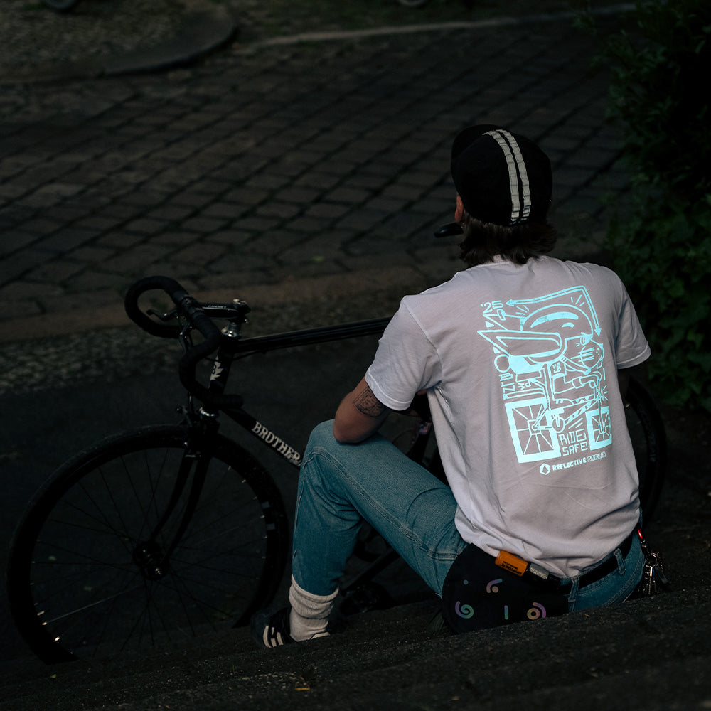 Man wearing reflective tshirt, sitting on on stairs 

