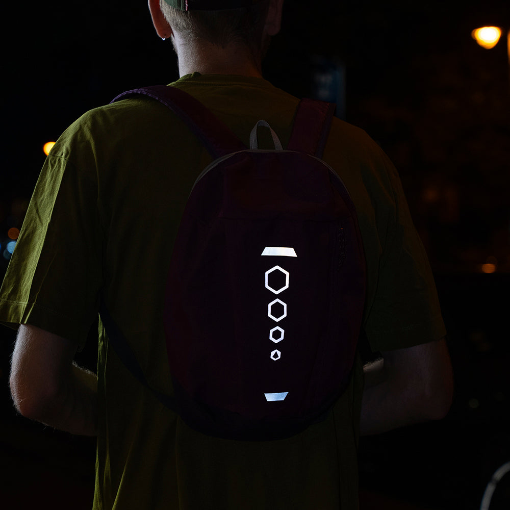 Reflective stickers applied on backpack worn by man at night in street