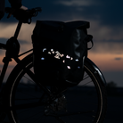 Gepäckträgertasche am Fahrrad mit reflektierenden Stickern vor Abenddämmerung