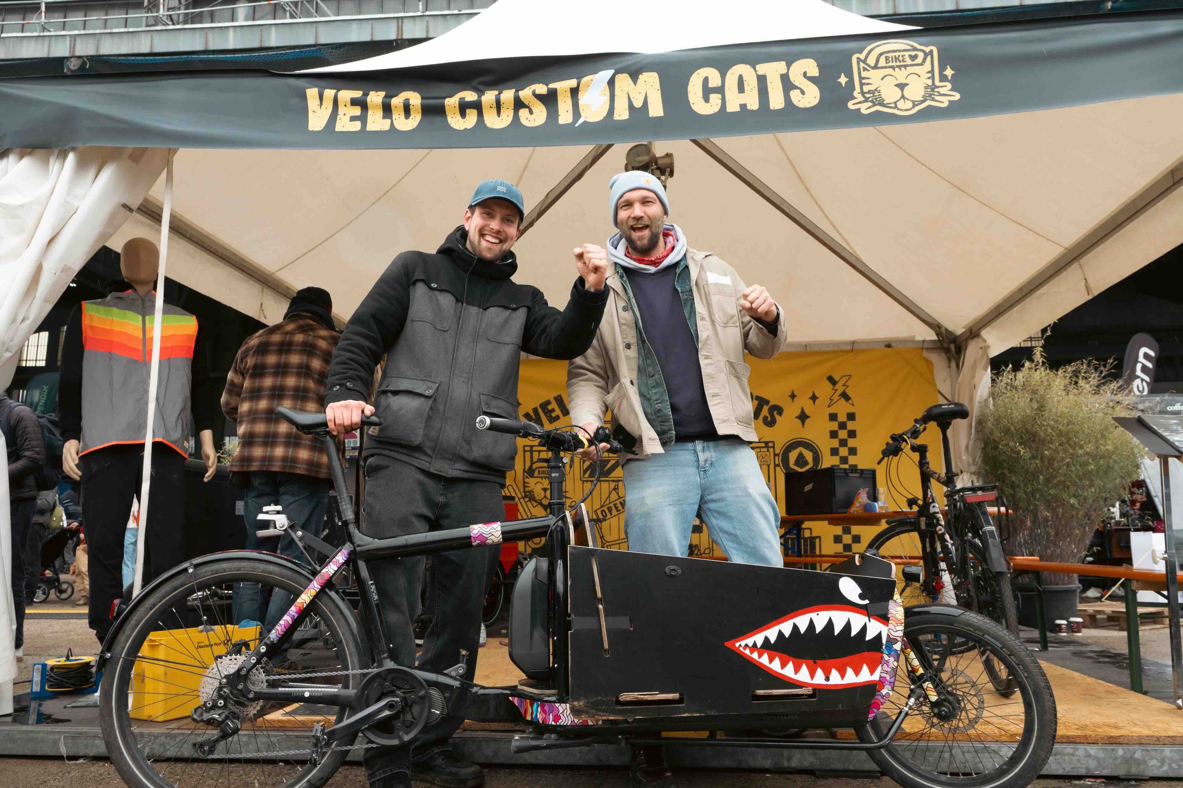 two guys in fornt of their bullitt cargobike cheering
