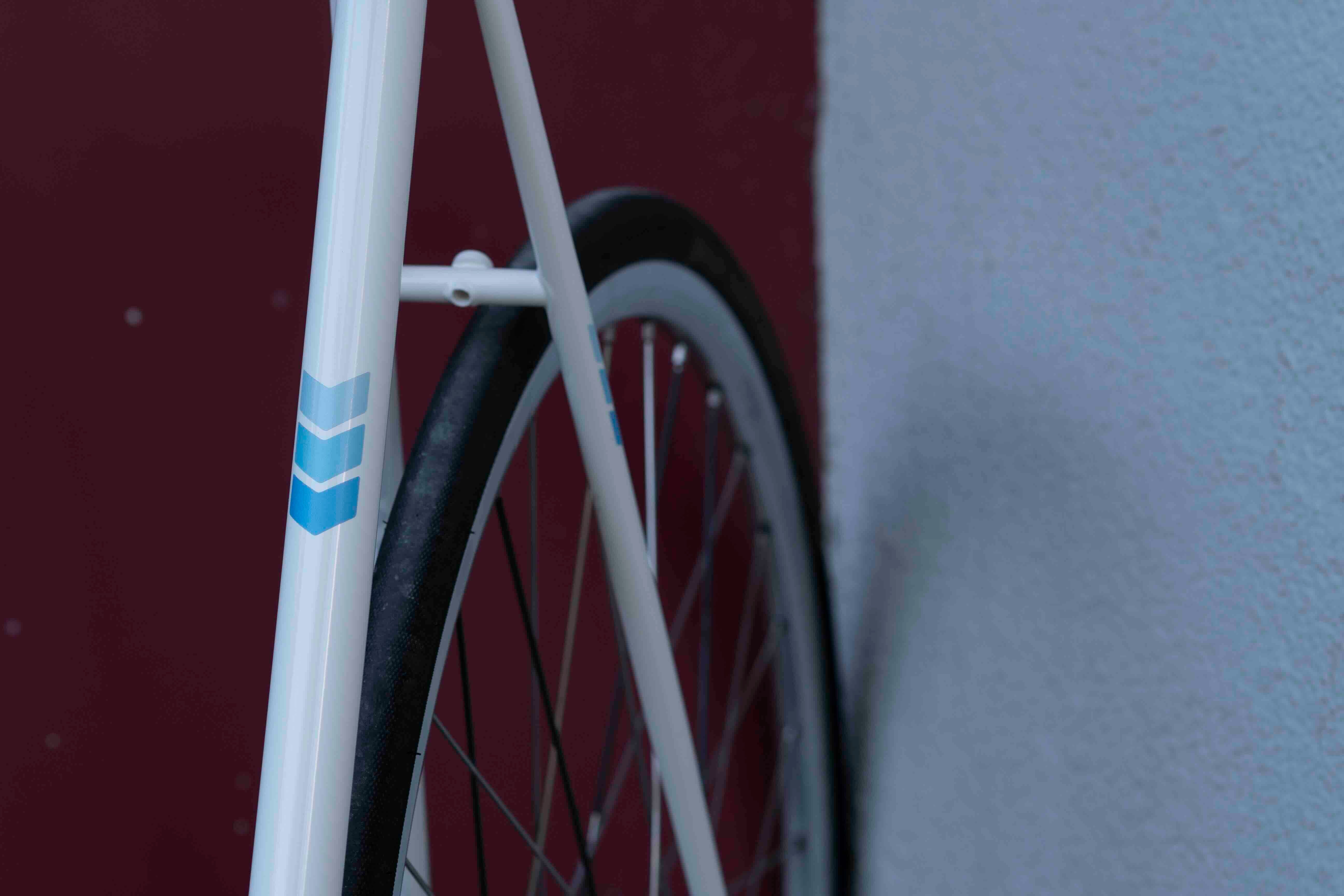 Chevrons Blue von REFLECTIVE Berlin auf weißem Fahrradrahmen mit stark reflektierenden blauen Pfeilformen für mehr Sichtbarkeit im urbanen Stil.