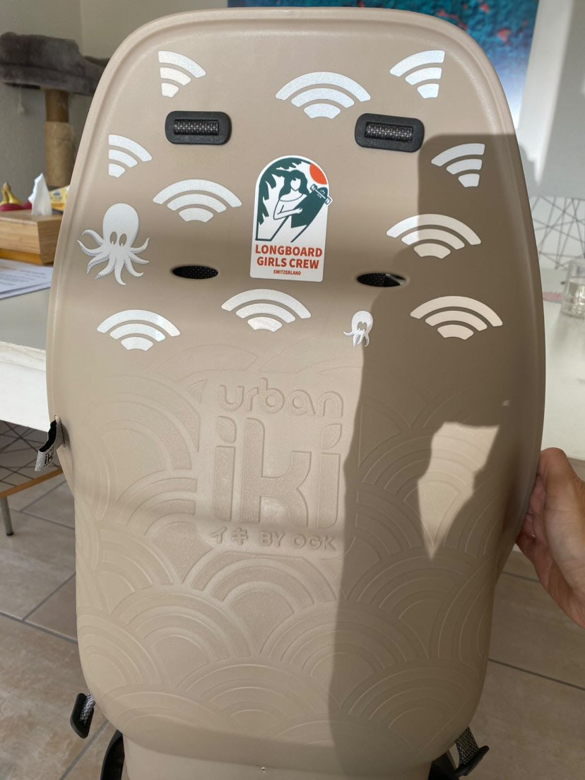 Oktopus Weiß und Sunrise Weiß von REFLECTIVE Berlin auf Kindersitz mit stark reflektierenden Meeres- und Linienformen für mehr Sichtbarkeit im urbanen Stil.