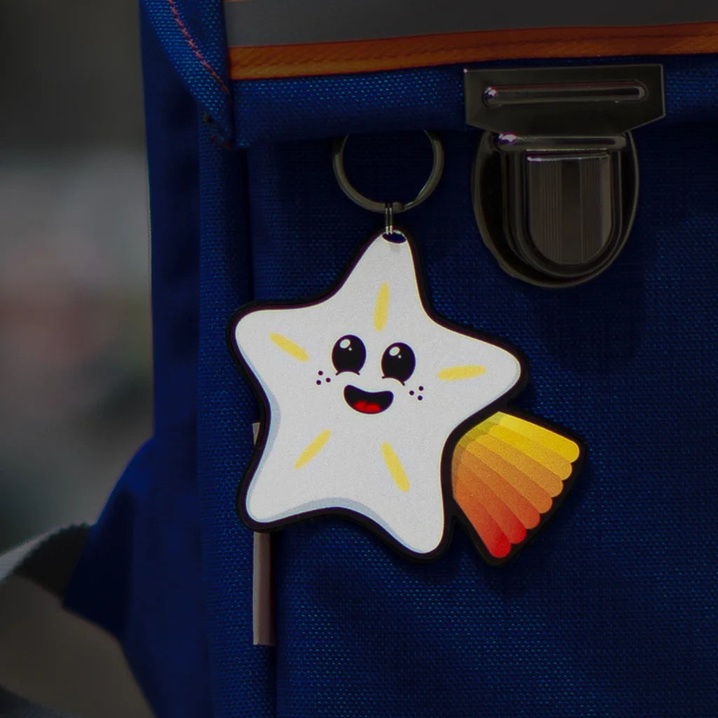 Reflektierender Anhänger ‚Reflective Hangers‘  in der Variante ‚Sterni’ an einem blauen Rucksack in der Dämmerung. Der Anhänger von REFLECTIVE Berlin reflektiert.