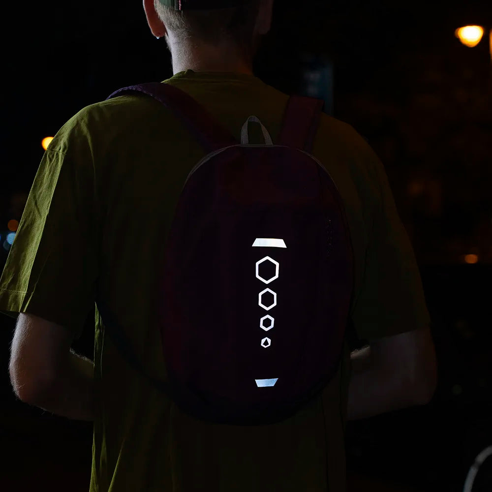 Reflektierende Aufkleber Textil Stoff „DIY“ in Farbvariante „weiß“ zum selbst zuschneiden. Die Sticker sind Streifen und Sechsecke zugeschnitten und auf einem lila Rucksack angebracht. Die Sticker reflektieren in der Dunkelheit. Von REFLECTIVE Berlin.