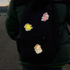 Reflektierende Aufkleber Stoff Textil Krokodil „Freddy“, Einhorn „Juno“ und Katze „Miez“ aus der Produktserie „Reflective Friends“  die auf einen schwarzen Rucksack geklebt sind der von einem Kind getragen wird. Von REFLECTIVE Berlin.